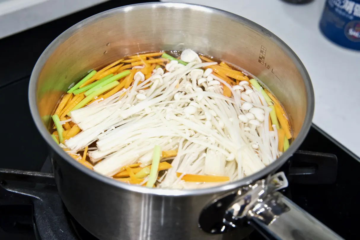依序汆燙紅蘿蔔絲、芹菜段、金針菇約30秒，燙好後瀝乾