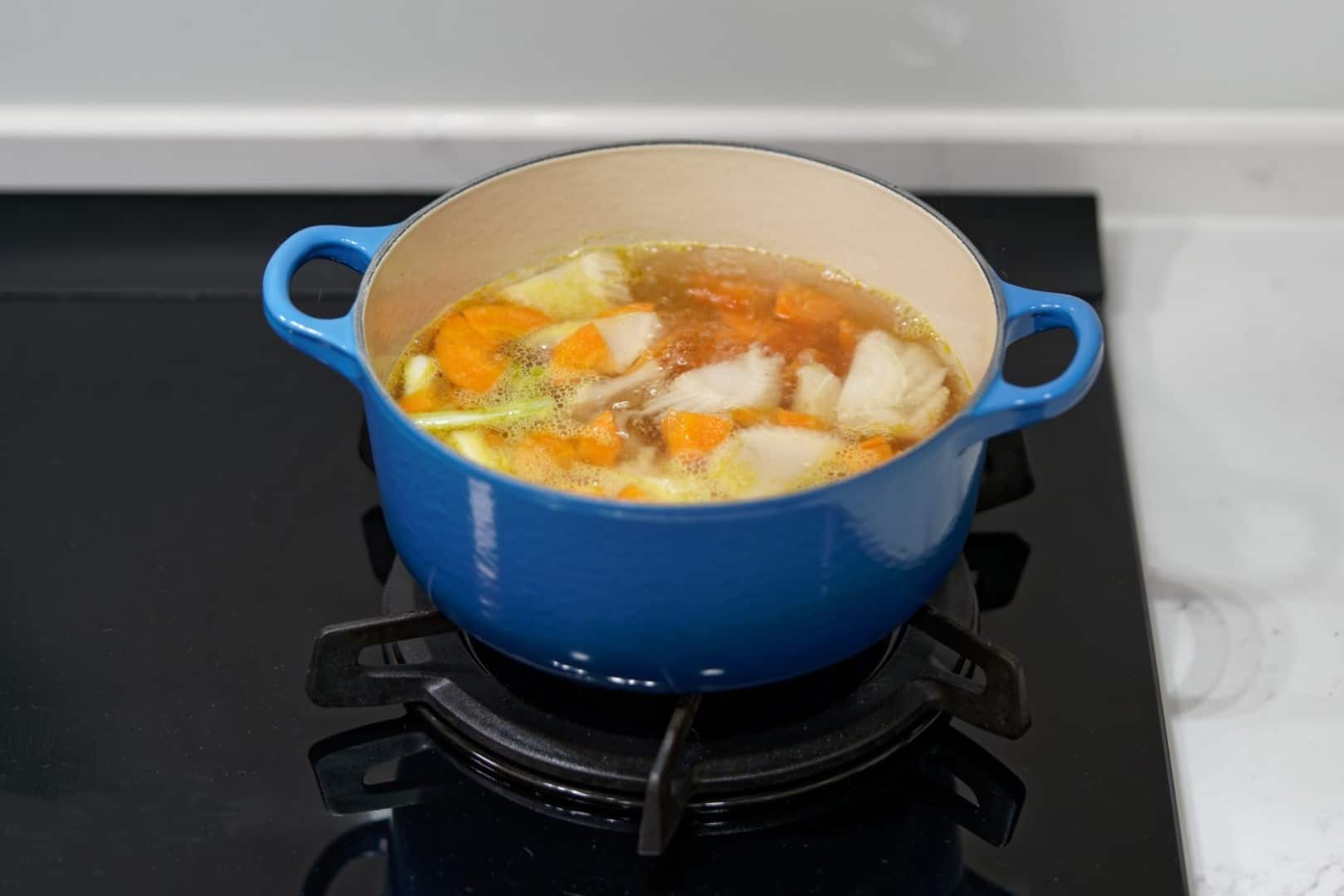 將炒香後的蔥白、酸白菜心與紅蘿蔔片放入高湯煮滾